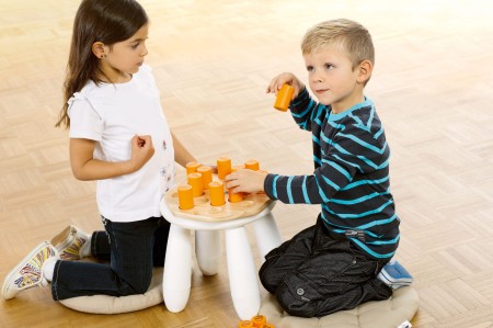 Pomarańczowe shakery na drewnianej podstawie gry Shake'n'Play dla dzieci w wieku przedszkolnym